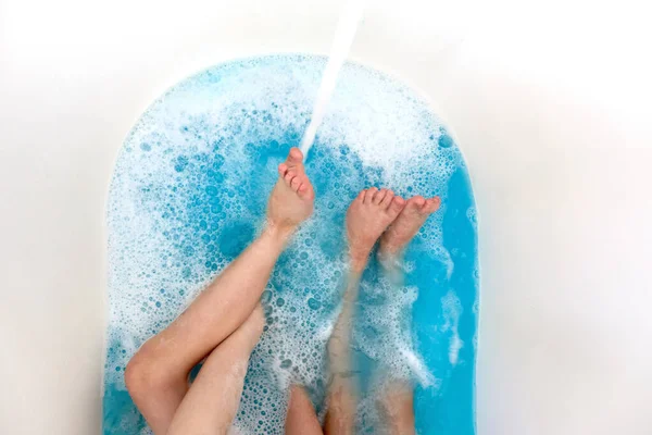 Jambes d'enfants dans la baignoire baignant dans l'eau bleue — Photo