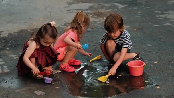 Children with toys playing in puddle — Stock Video