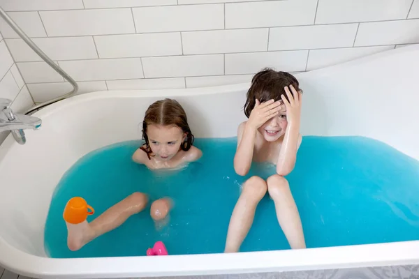 Aranyos testvérek fürdés fürdőkádban együtt kék vízben — Stock Fotó