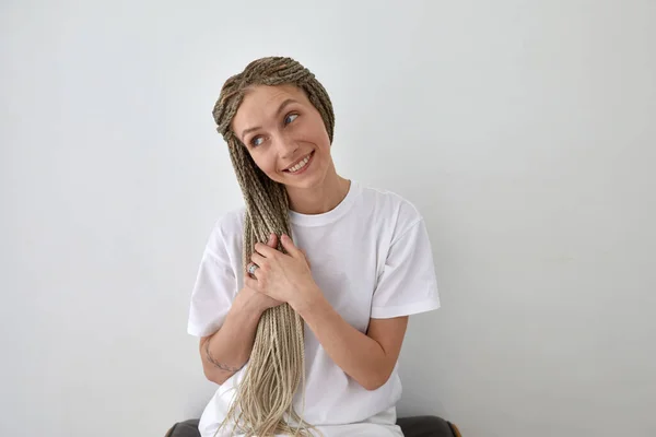 Улыбающаяся женщина нежно касается плетеных волос — стоковое фото
