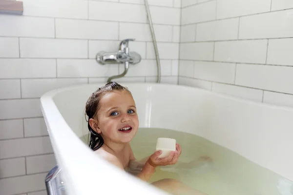 Glimlachend meisje het hebben van bad in bad badkamer Stockafbeelding