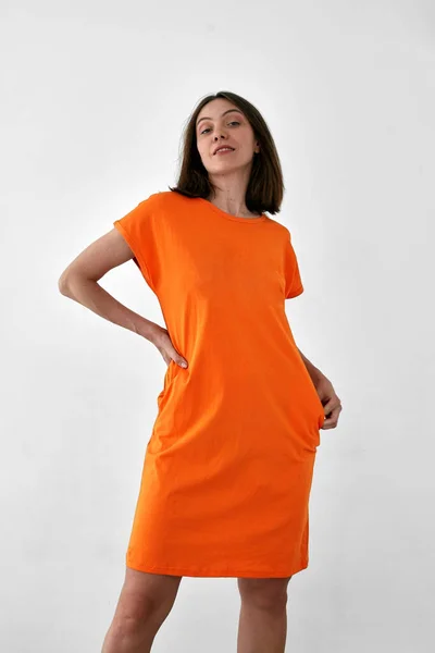 Красивая женщина в оранжевом платье белый фон — стоковое фото
