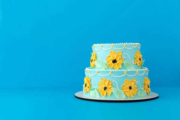 Uroczysty tort z kolorowym kwiatowym wystrojem niebieskie tło — Zdjęcie stockowe