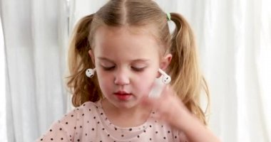 Küçük komik kız kulaklıklarını çıkarıyor.