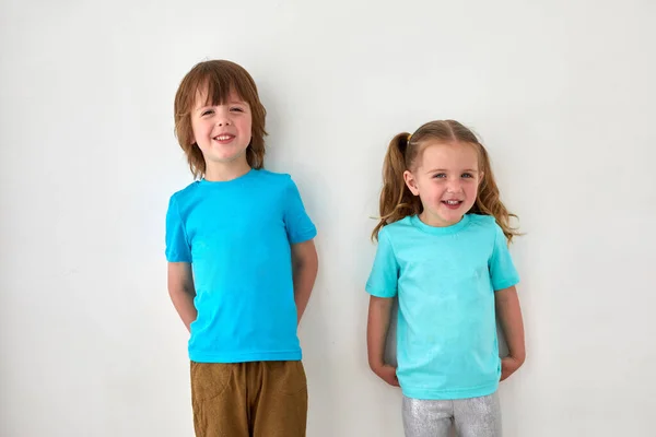 Leuke broers en zussen in blauwe t-shirts tegen grijze muur Stockafbeelding