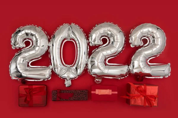 Cutii cadou lângă numărul 2022 baloane fundal roșu — Fotografie, imagine de stoc