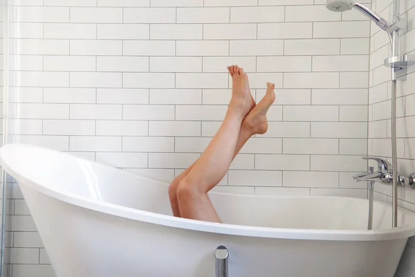 Anonymous barefoot woman chilling in white bathtub — Stock Photo, Image