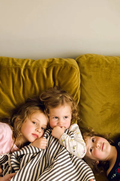 Imádnivaló nővérek ülnek együtt a kanapén. — Stock Fotó