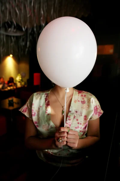 woman hiding her face behing white balloon