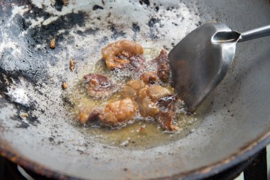 Sıcak bir tencerede kızartılır yalın domuz eti.
