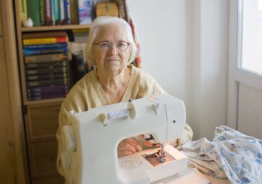 İşyerindeki yaşlı kadın dikiş makinesinin yanında. 