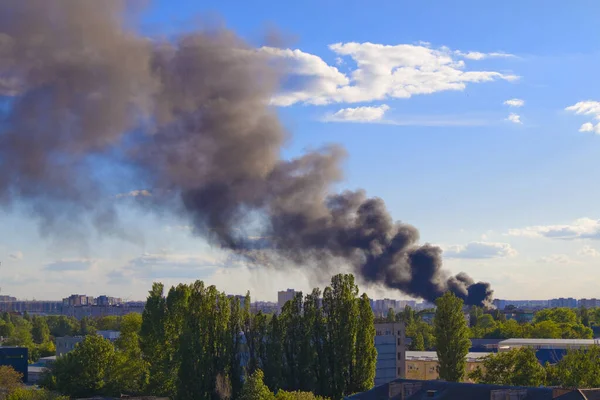 Black smoke from the fire in front of blue sky