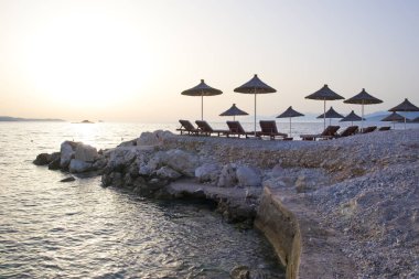 Arnavutluk 'un Ksamil kentinde güneş yatakları ve şemsiyeli plaj