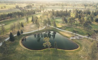 Golf sahasında gün doğumu Ağaçlar, göller ve yollar.