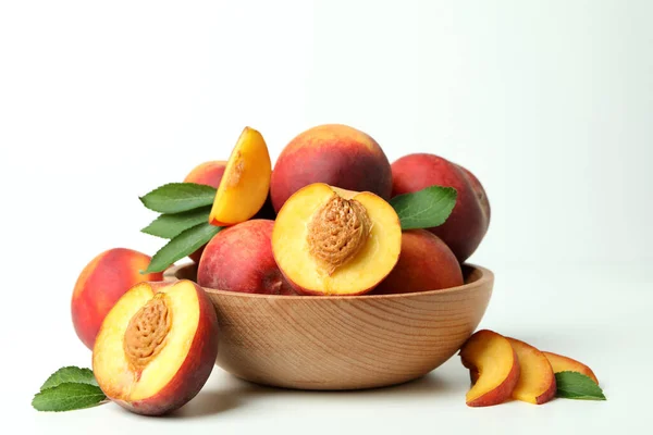 白いテーブルの上に桃の果物と木製のボウル — ストック写真