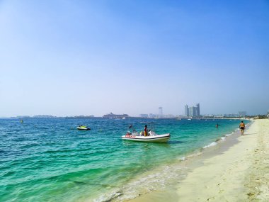 Suyun üzerinde tekne ve jet ski ile sahil hattı ve F 'deki binalar.