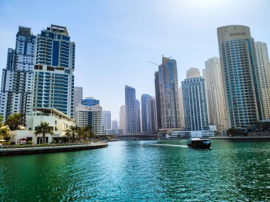 Köprüsü, teknesi, solunda palmiye ağaçları olan bir nehir.