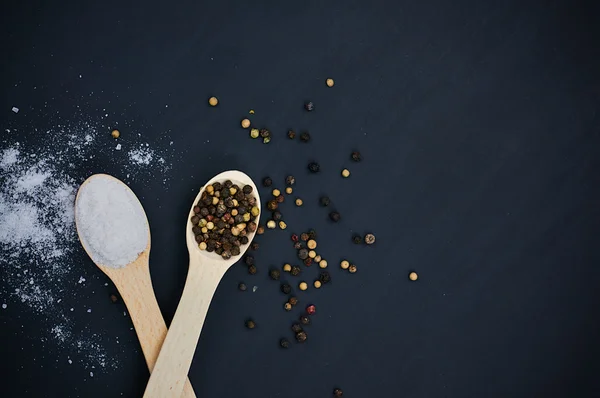 Salt and pepper on wooden spoons — Stock Photo, Image