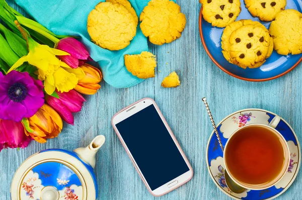 Telefone e xícara de chá com biscoitos . Fotos De Bancos De Imagens Sem Royalties