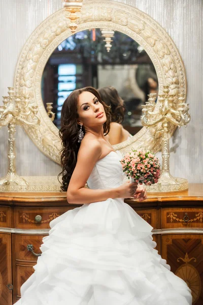Bride in white wedding dress and mirror behind