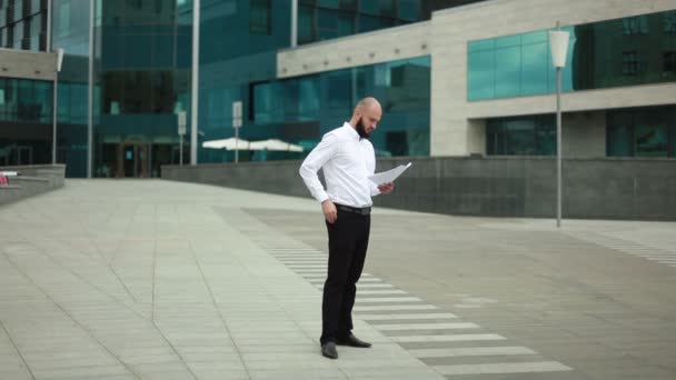 Uomo d'affari gettando carta vicino edificio per uffici — Video Stock