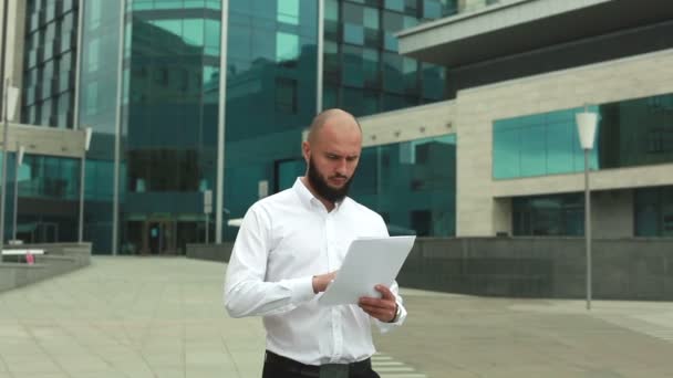 Человек с бородой в рубашке с документами — стоковое видео