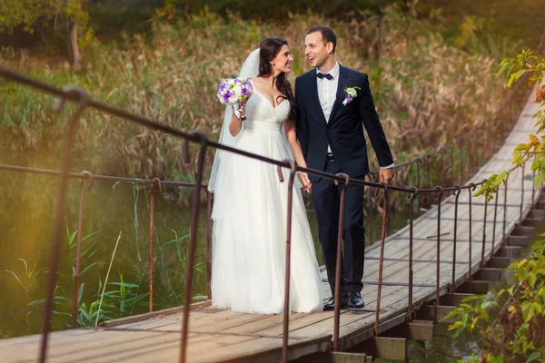 Novia y novio en el puente sobre el río — Foto de Stock