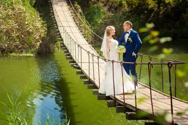 Bruden och brudgummen utomhus på bro — Stockfoto