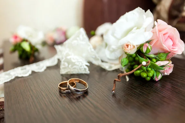 Anéis de casamento na mesa perto de flores — Fotografia de Stock