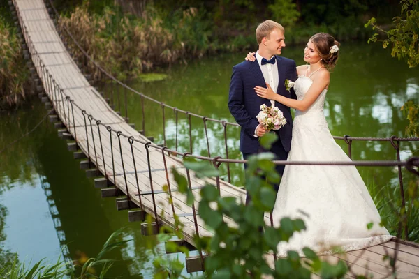 Knuffelen bruidegom bruid op de brug — Stockfoto