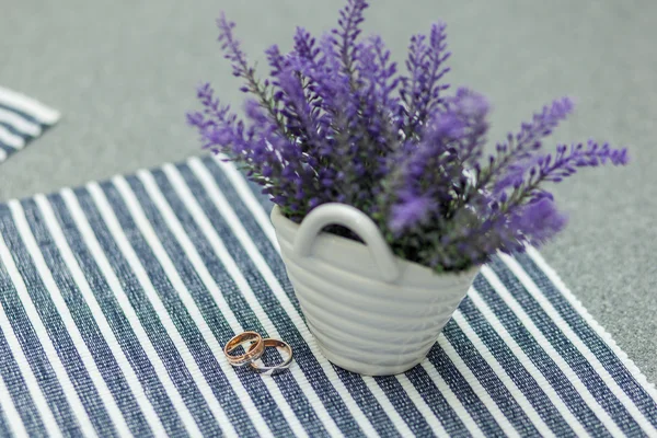 Обручальные кольца возле вазы с лавандой на скатерти — стоковое фото