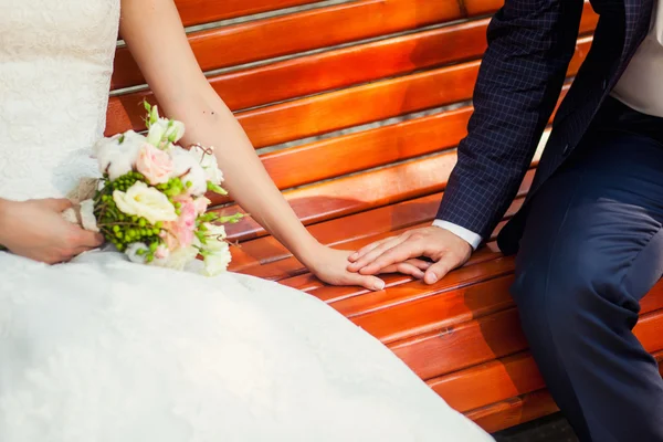 Couple hand in hand on wooden bench — Stock Photo, Image