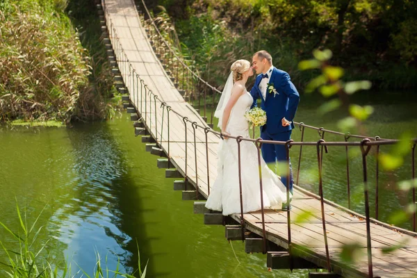 Brudparet kysser på river bridge — Stockfoto