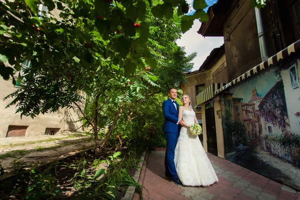 Brudgummen med bruden i park nära fashionabla byggnad — Stockfoto