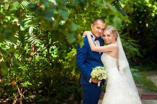 Brudgummen med bukett och bruden i park — Stockfoto