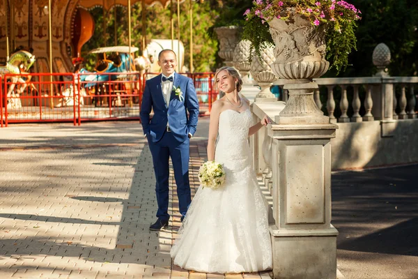 Wedding couple near sculpture in park — Stock Photo, Image