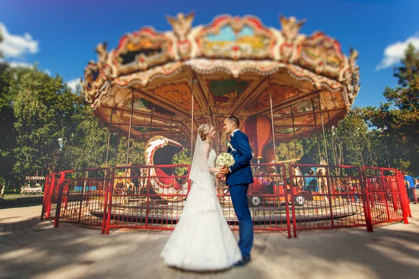 Casamento casal no parque perto de carrossel — Fotografia de Stock