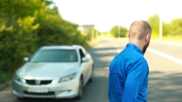 Mannen med skägg visar nycklar från bil går till sin bil och sätter i den — Stockvideo