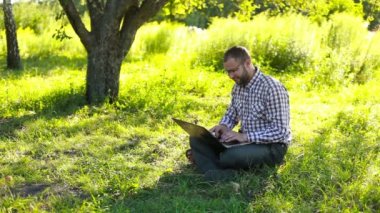 Laptop alanında yazarak ve gülümseme ile kameraya bakıp mutlu adam