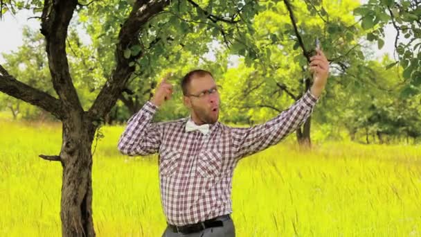 Jonge man in glazen maken grappige selfie in de weide — Stockvideo