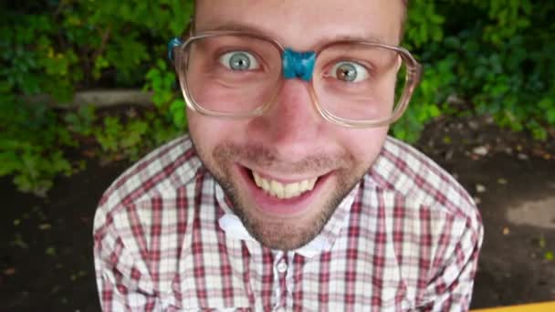 Junger Mann mit Brille starrt in die Kamera und lacht hysterisch — Stockvideo