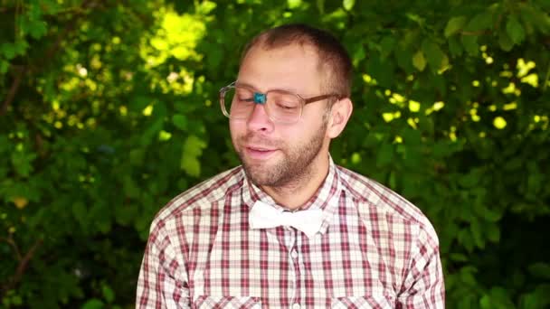 Jeune homme à lunettes regardant dans la caméra, fixant son noeud papillon et riant — Video