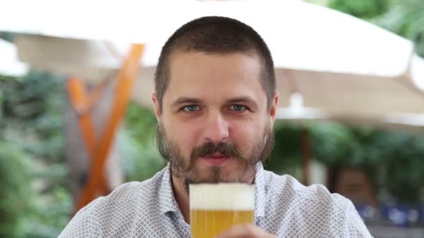 Junger Mann trinkt Bier mit Schaum und wischt sich die Nase — Stockvideo