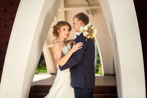 Nevěsta a ženich pod kamenným obloukem — Stock fotografie