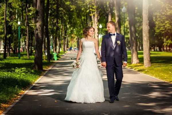 Casal em vestidos de noiva de mãos dadas no parque — Fotografia de Stock