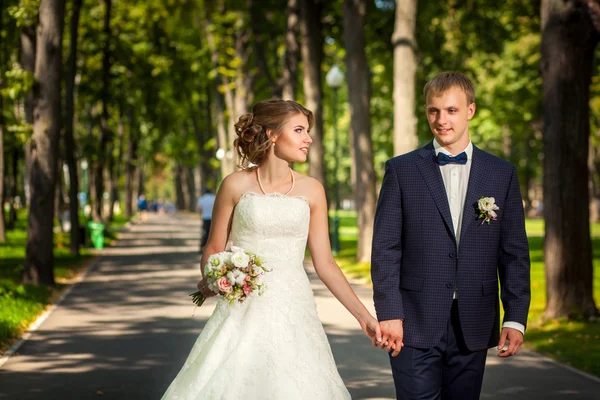 Novia y novio en el parque a lo largo de la pasarela —  Fotos de Stock