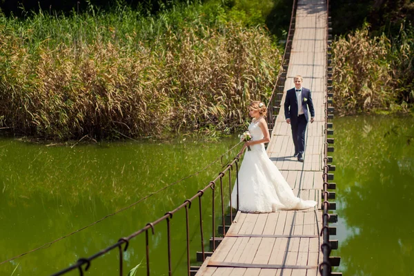 Novio yendo a la novia a lo largo del puente — Foto de Stock