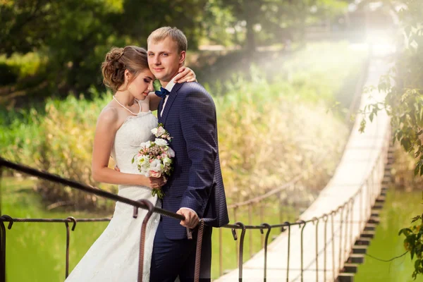 Bruid en bruidegom buiten op de brug — Stockfoto