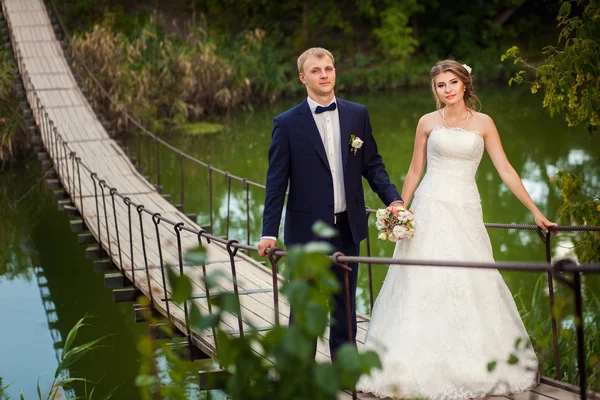 Boda pareja caminando en puente colgante — Foto de Stock