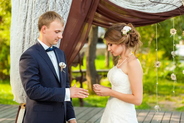 Nevěsta na sobě kruh blízko svatební oblouk — Stock fotografie